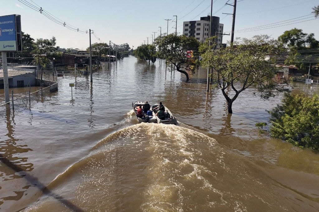 Aerial view showing rescuers navigating the flooded streets by boat in Porto Alegre, Brazil, on May 6, 2024, after torrential storms in the southern Rio Grande do Sul State. The rains may have abated, but floodwaters on Monday continued their assault on south Brazil, with hundreds of municipalities in ruins and food and drinking water fast running out. Since the unprecedented deluge started last week, at least 83 people have died, 111 are missing and more than 129,000 were ejected from their homes by floods and mudslides in Rio Grande do Sul state, authorities said. (Photo by Carlos FABAL / AFP)
