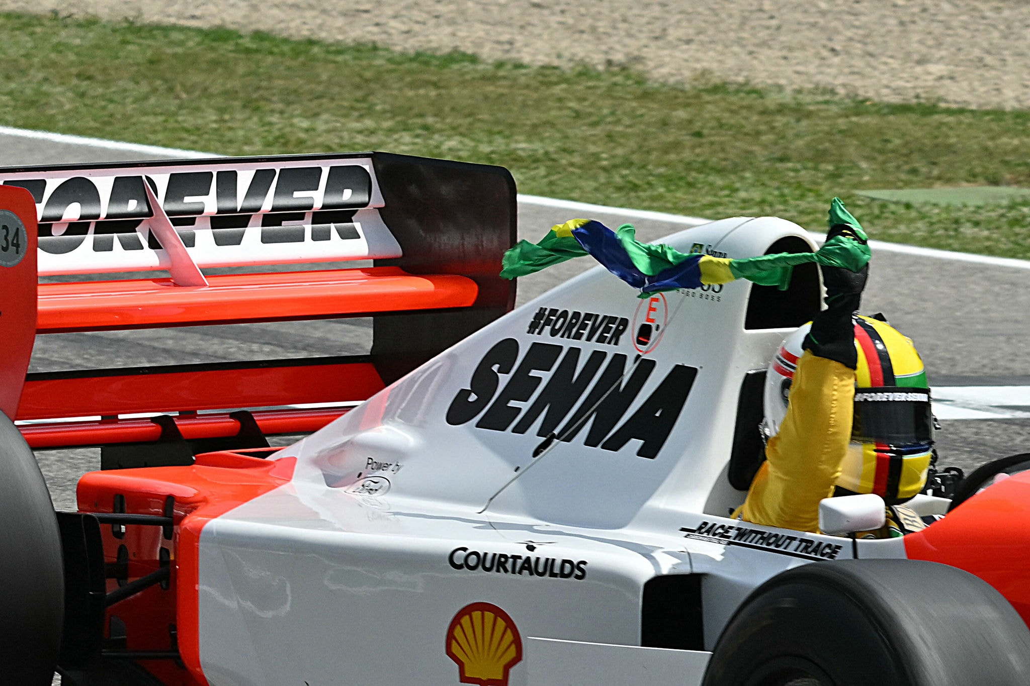 German former Formula One champion Sebastian Vettel holds a Brazilian flag as he drives the historic McLaren car of late Brazilian driver Ayrton Senna, to mark 30th anniversary of his death, during the drivers' parade prior to the Emilia Romagna Formula One Grand Prix at the Autodromo Enzo e Dino Ferrari race track in Imola on May 19, 2024. The 34-year-old Brazilian Formula One champion Ayrton Senna was leading at Imola on May 1, 1994, when he went off the track at the Tamburello curve and smashed into a concrete wall. (Photo by ANDREJ ISAKOVIC / AFP)