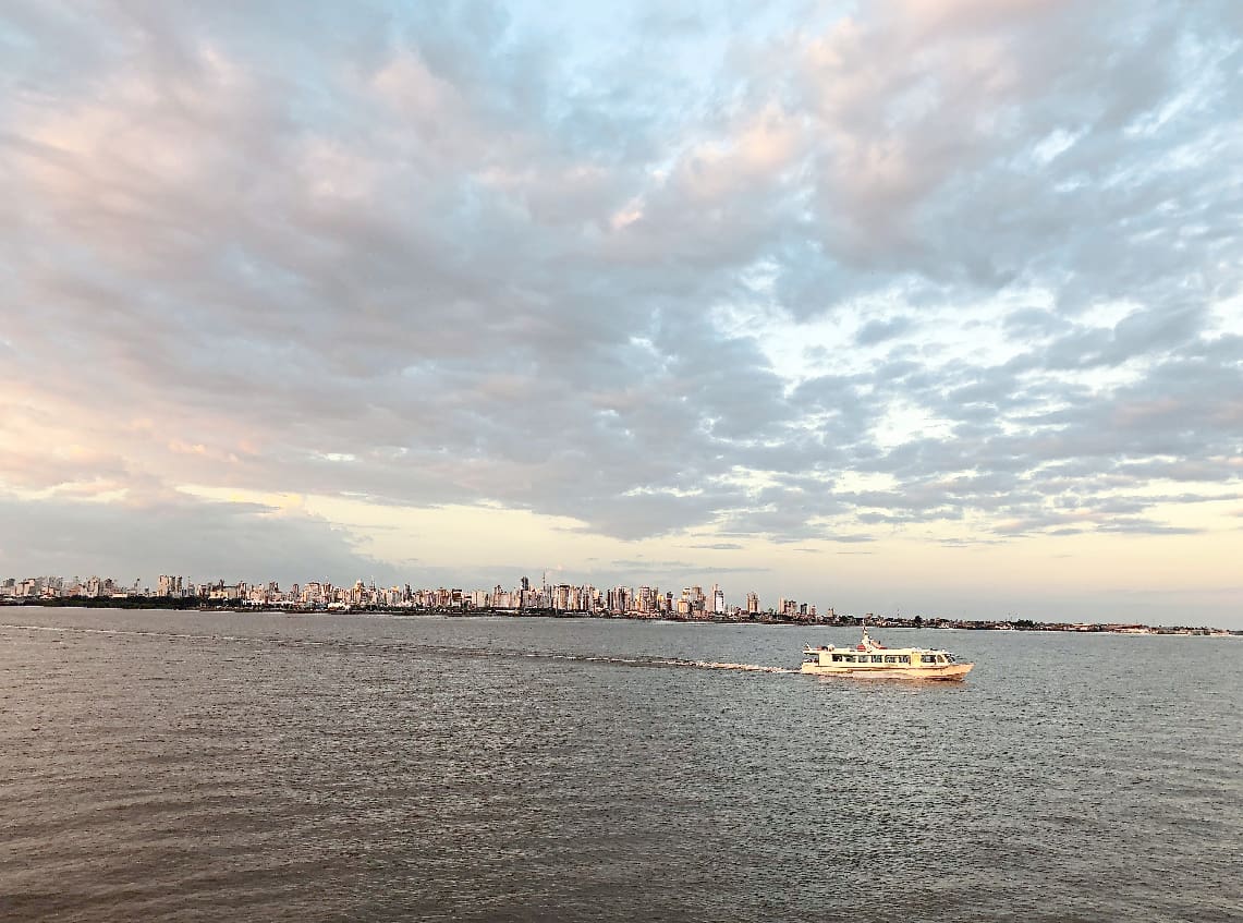 Embarcação navega na Baía do Guajará, com os prédios da capital paraense ao fundo: passeios por rio e terra