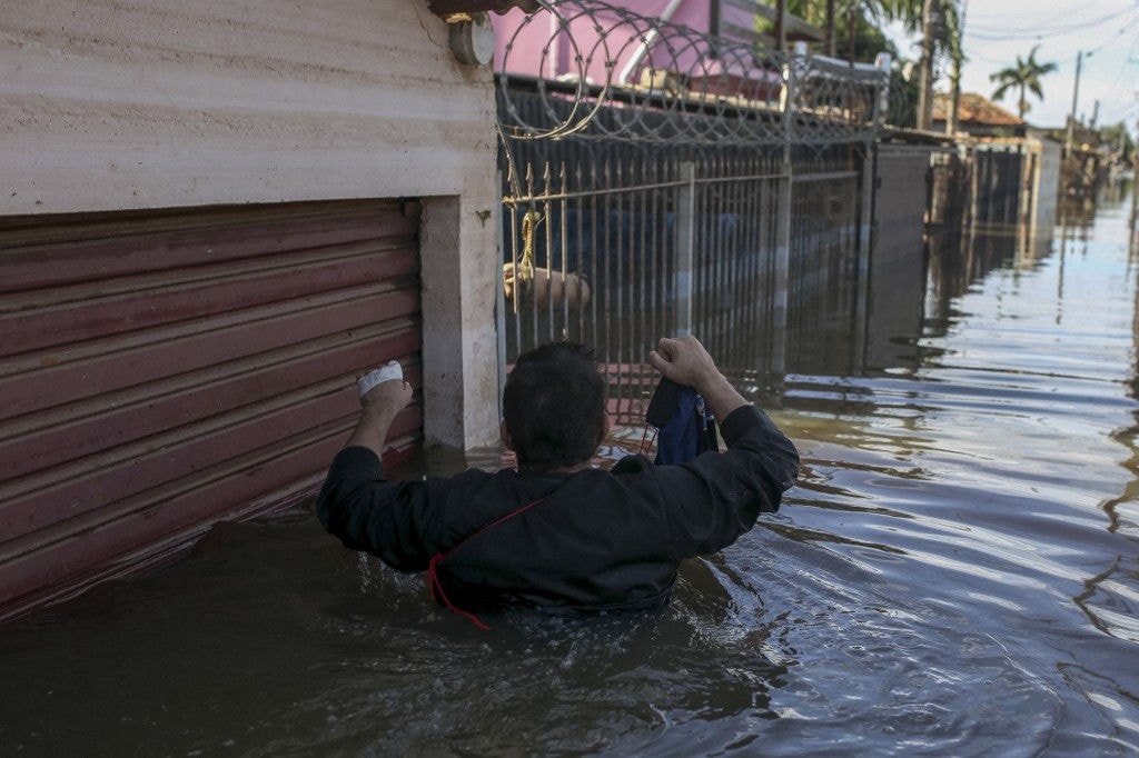 Homem caminha por rua alagada em Canoas, uma das cidades mais afetadas pelas enchentes no Rio Grande do Sul