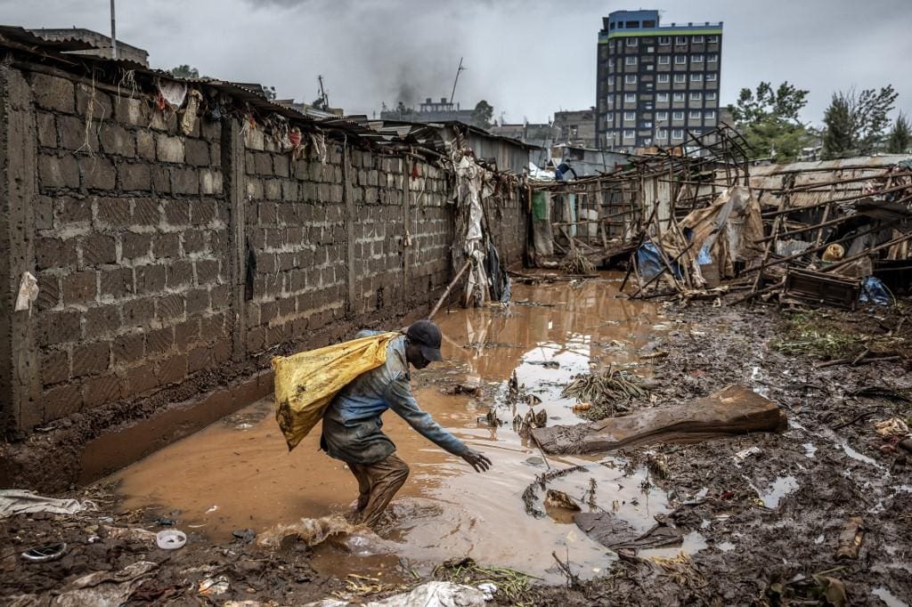 Um homem carrega alguns pertences numa área fortemente afetada por inundações, em Nairobi