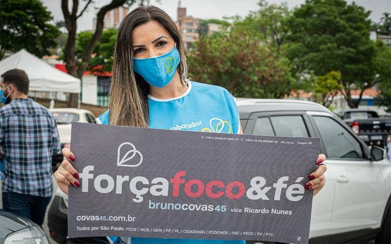 Mulher segura propaganda da campanha de Bruno Covas e Ricardo Nunes; empresa de família de candidato a vice recebeu de creches conveniadas a Prefeitura