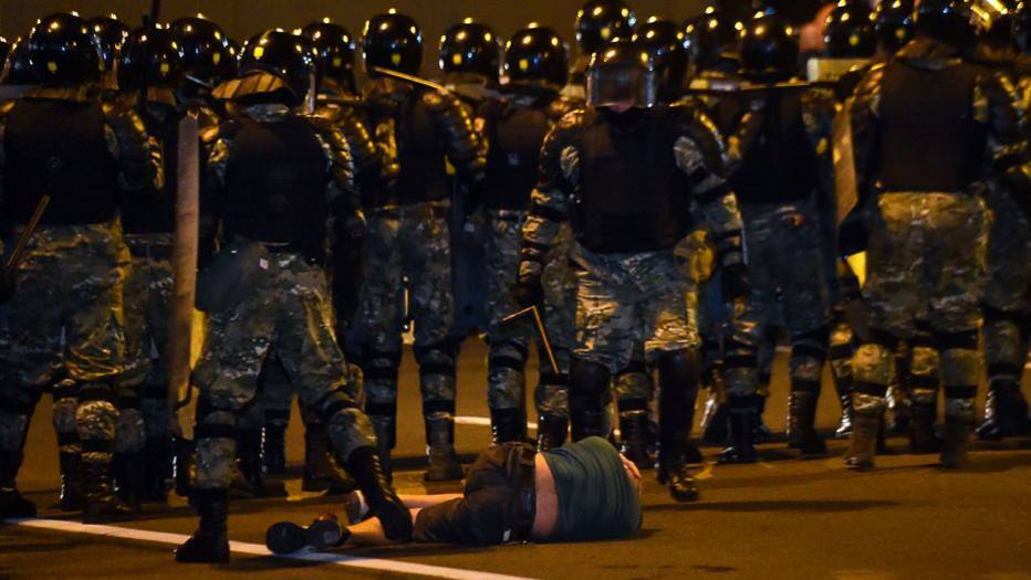 Homem deitado no chão é agredido por policial durante protesto