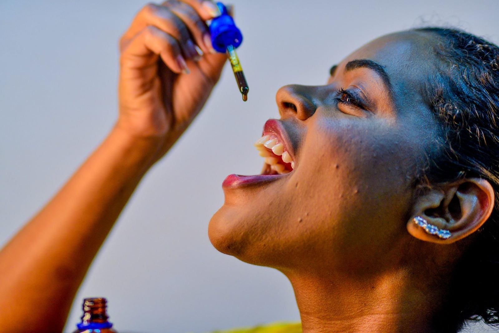 Foto mostra mulher pingando gota de remédio à base de maconha