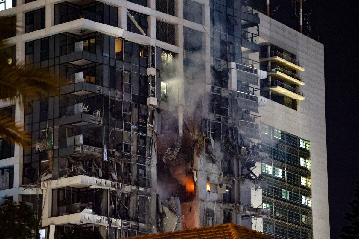 Fire and smoke rise from a building, reportedly hit by a missile fired from Iran, in central Tel Aviv on June 13, 2025. Iran fired a barrage of ballistic missiles at Israel in a counter-strike in the evening on June 13, after an unprecedented onslaught hammered the Islamic republic's top military brass and targeted its nuclear facilities and bases. (Photo by Jack GUEZ / AFP)