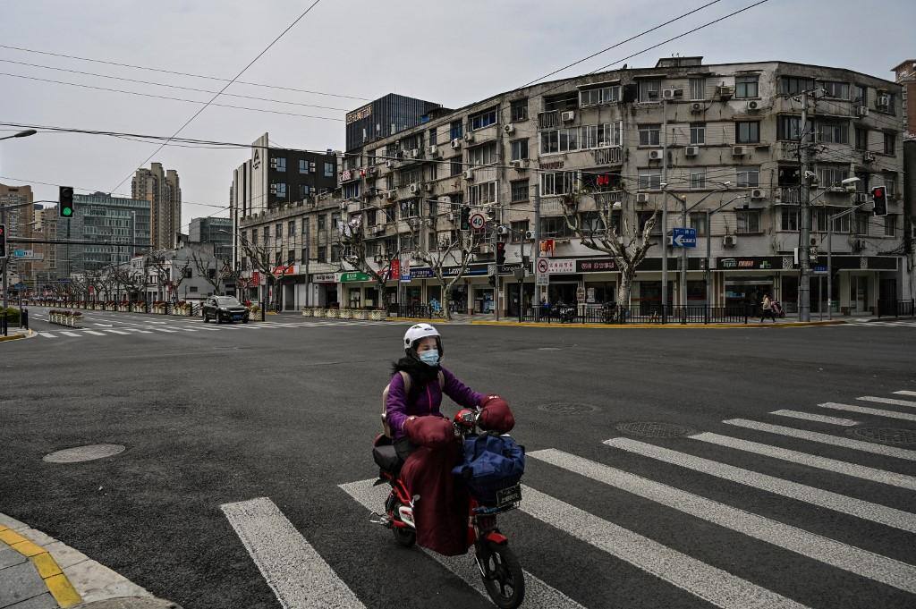 Uma mulher dirige uma scooter por uma rua tranquila no distrito de Yangpu, em Xangai, em 28 de março de 2022. Milhões de pessoas no centro financeiro da China ficaram confinadas em suas casas em 28 de março, quando a metade leste de Xangai entrou em confinamento para conter a maior crise do país