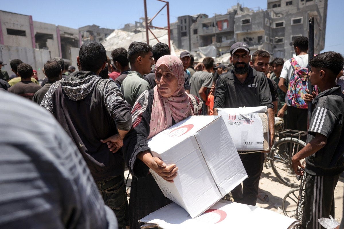 Palestinians carry away food parcels donated by the Emirates Red Crescent, from a distribution point supervised by volunteers from Palestinian families organised in committees to prevent theft, in Gaza City on June 26, 2025. (Photo by BASHAR TALEB / AFP)