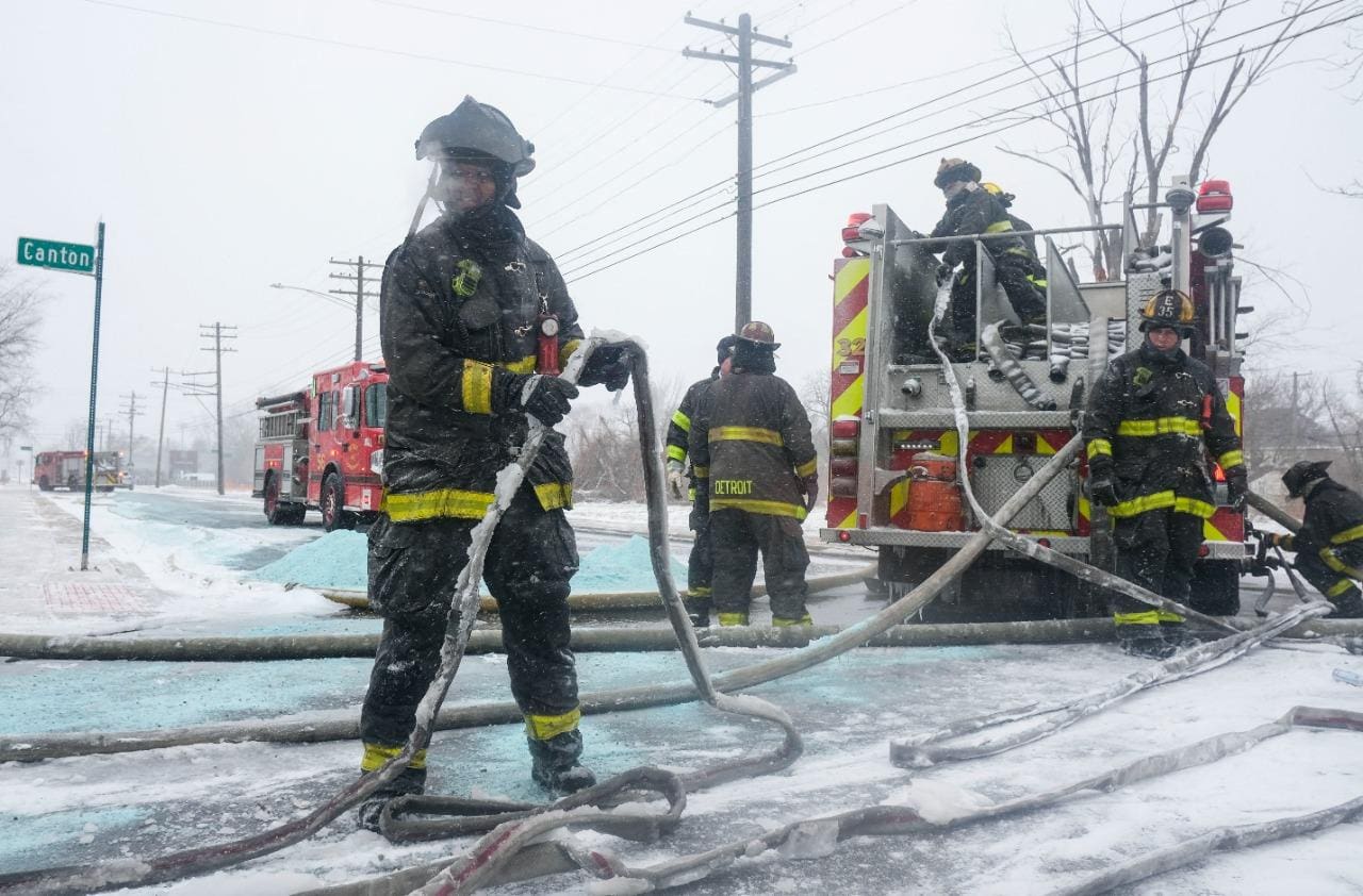 ALT Bombeiros do Corpo de Bombeiros de Detroit tentam remover o gelo das mangueiras enquanto combatem um incêndio em um armazém