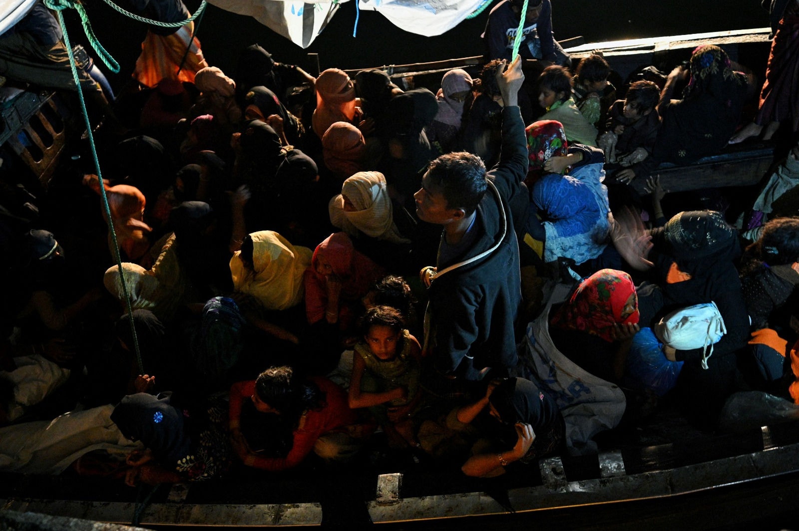 Refugiados Rohingya sentam-se em um barco de madeira após serem resgatados pela marinha da Indonésia nas águas ao largo de Bireuen, ao chegarem ao porto de Krueng Geukueh em Lhokseumawe, na costa norte da província de Aceh, em 31 de dezembro de 2021