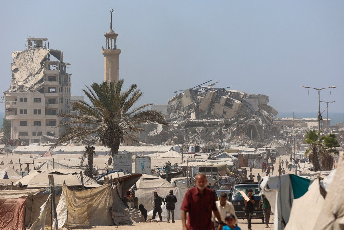 Palestinos passam perto dos destroços da Torre Mushtaha na Cidade de Gaza 