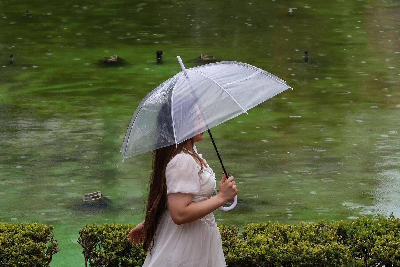 Garota com guarda-chuva branco durante chuva na Praça da Liberdade