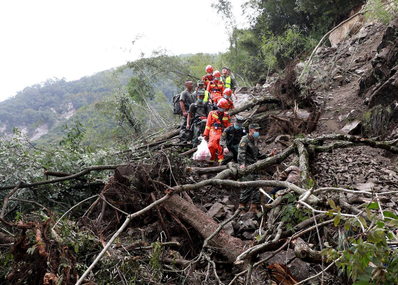 Equipes de resgate passando por árvores arrancadas de um deslizamento de terra enquanto se dirigem para uma área afetada pelo terremoto, em Sichuan