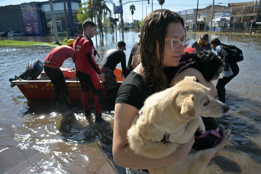 Firefighters take people out in boats, following floodings due to heavy rains in Porto Alegre, Rio Grande do Sul state, Brazil on May 6, 2024. From top to bottom, rescuers scour buildings in Porto Alegre for inhabitants stuck in apartments or on rooftops as unprecedented flooding killed at least 78 people in the southern state, with dozens missing and some 115,000 forced to leave their homes. (Photo by NELSON ALMEIDA / AFP)