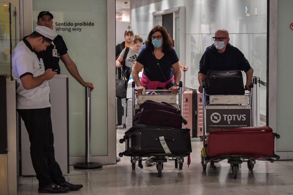 Passageiros desembarcam no aeroporto de Guarulhos, em São paulo, com máscaras