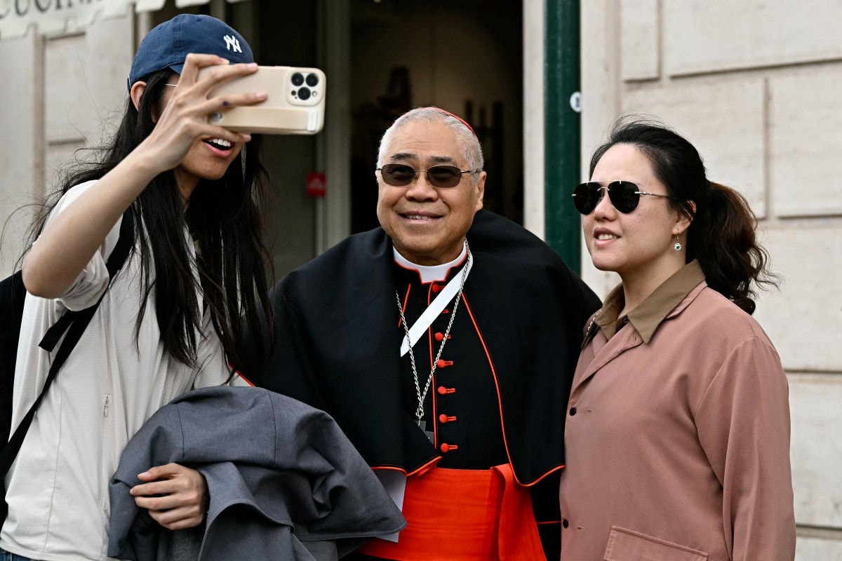 Archbishop of Singapore, cardinal William Goh Seng Chye poses with tourists in Via della Conciliazione after a congregation meeting at The Vatican, on May 5, 2025. (Photo by Gabriel BOUYS / AFP)