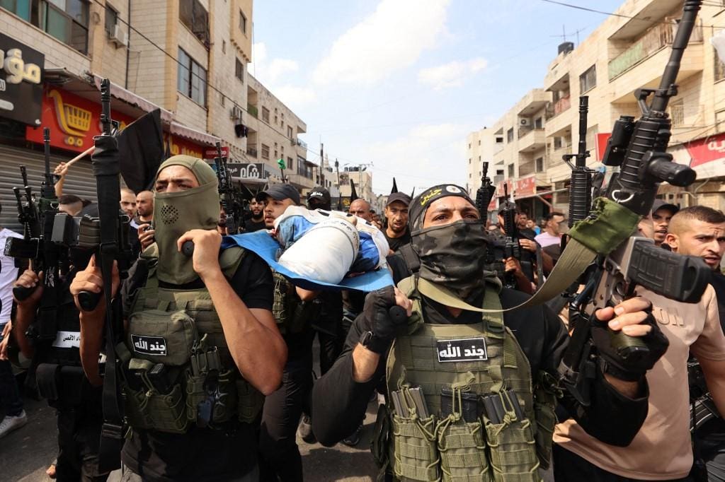 Militantes palestinos carregam o corpo de Ahmad Awawda, de 19 anos, morto em confrontos com tropas israelenses na região ocupada de Nablus, na Cisjordânia, durante seu funeral em Jenin, em 8 de outubro de 2023