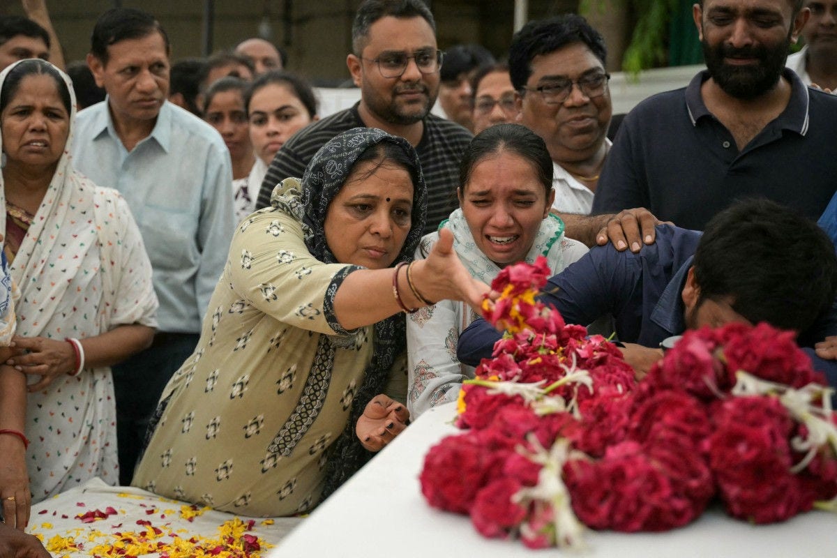 Relatives mourn near the coffins of victims, who were killed in the Air India flight crash, during a special prayer before the funeral ceremony in Ahmedabad on June 15, 2025. Grieving families held funerals in India on June 15 for their relatives who were among at least 279 killed in one of the world's worst plane crashes in decades. (Photo by Dibyangshu SARKAR / AFP)