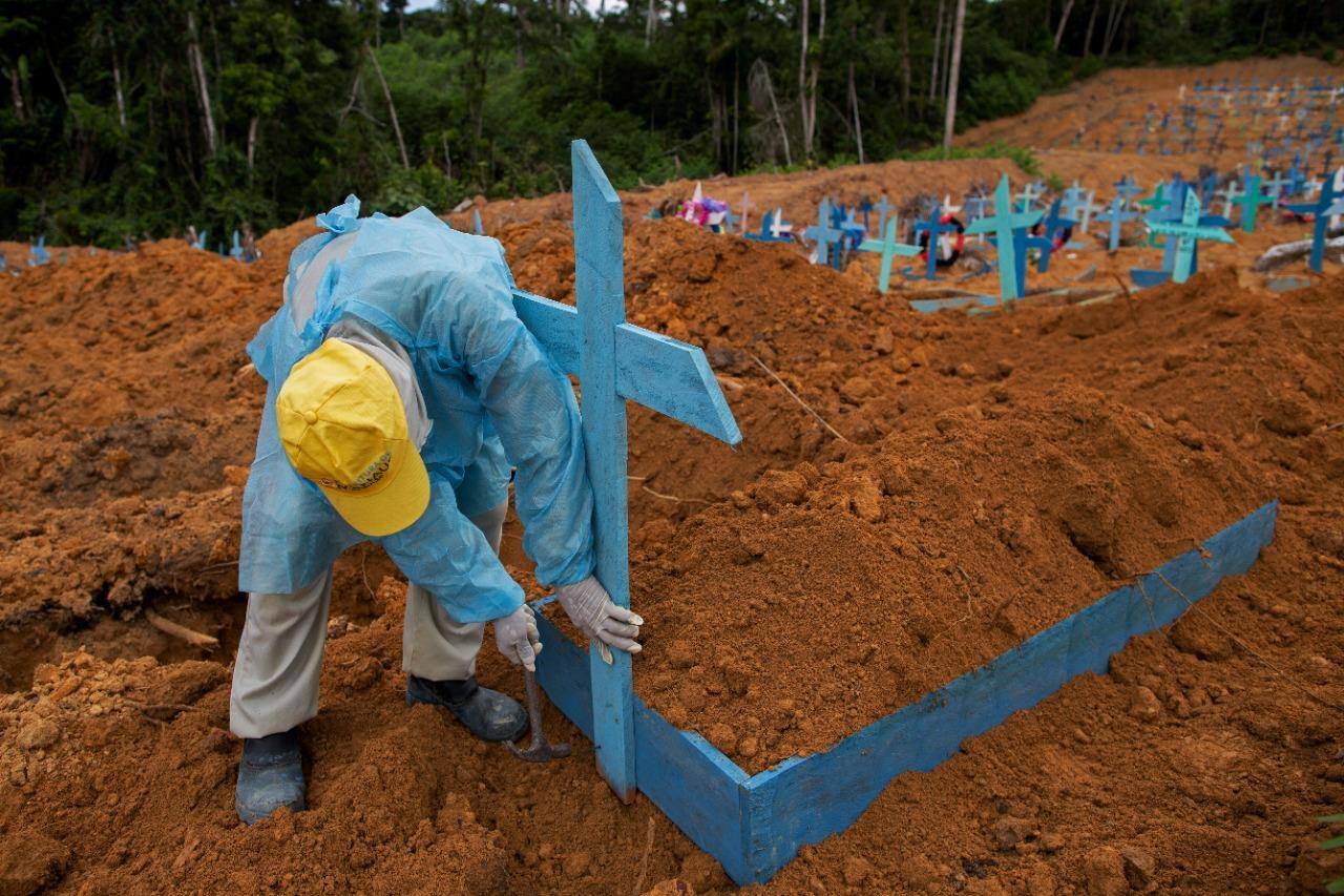 Trabalhador do cemitério Nossa Senhora Aparecida em Manaus coloca uma cruz em área reservada para sepultamento das vítimas da covid-19