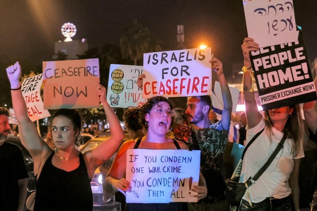Manifestantes, em Tel Aviv, mostram cartazes que pedem cessar-fogo em Gaza