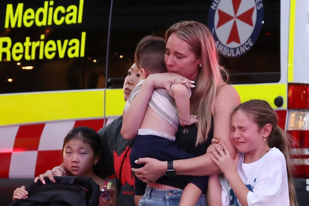 Mulher abraçada a crianças deixa o local do ataque em shopping de Sydney, na Austrália