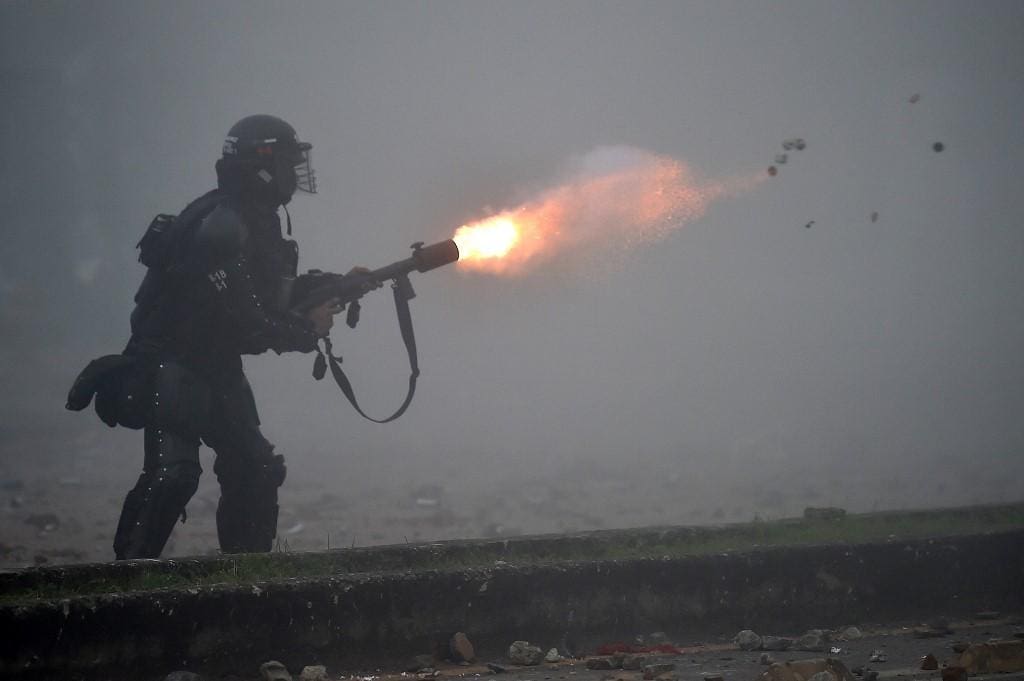 Um policial de choque dispara gás lacrimogêneo contra manifestantes durante confrontos na Colômbia