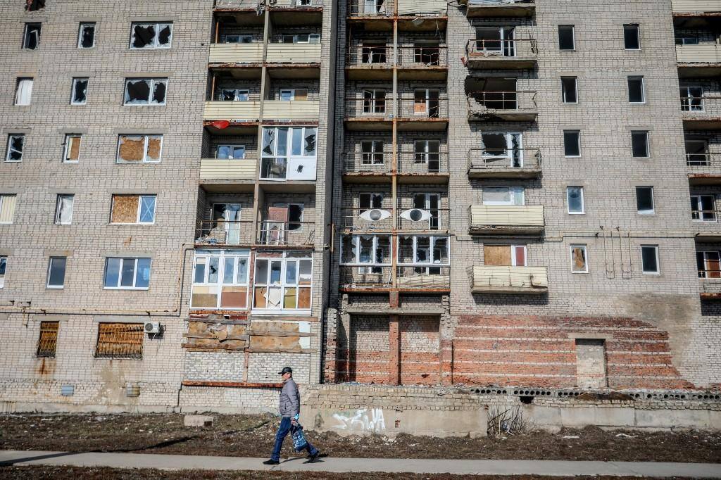 Ucraniano caminha diante de prédio abandonado em Donetsk, na fronteira da Ucrânia com a Rússia