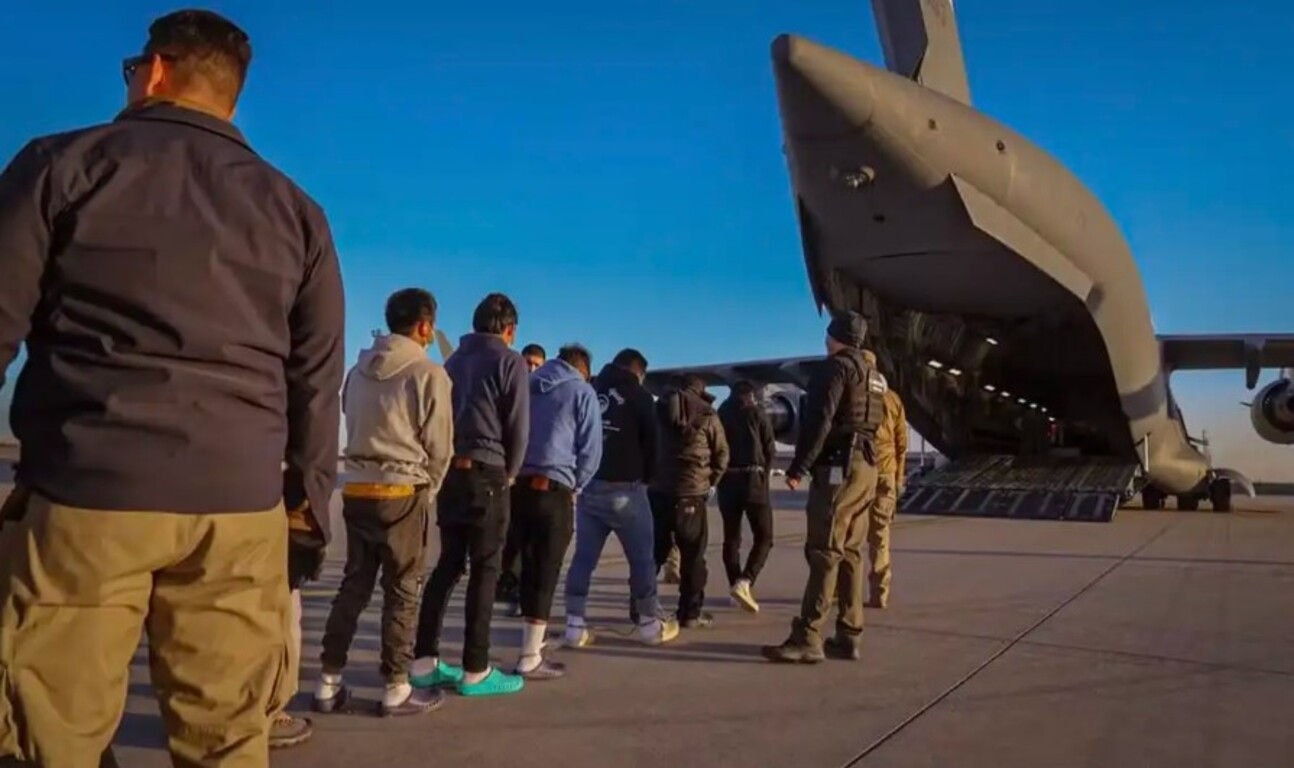 Migrantes presos embarcam em avião da força aérea dos EUA para serem deportados