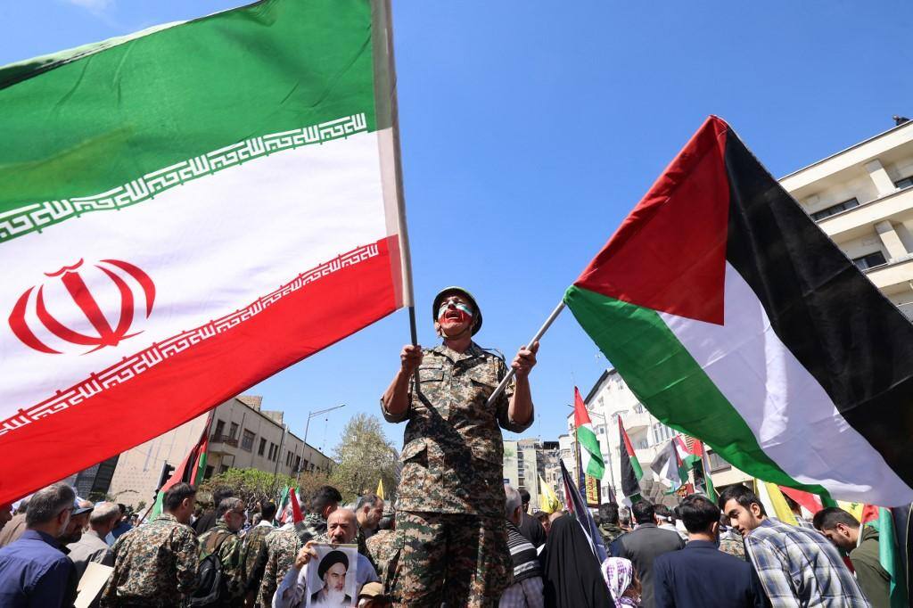 Iraniano segura bandeira do Irá e da Palestina durante ato em Teerã no qual foram lembradas as mortes de oficiais no bombardeio de Israel e complexo diplomático iraniano em Damasco