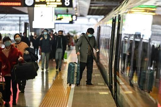 Pessoas que usam máscaras como medida preventiva contra o novo coronavírus COVID-19 embarcam em um trem, uma das paradas é Wuhan, em uma estação de Xangai