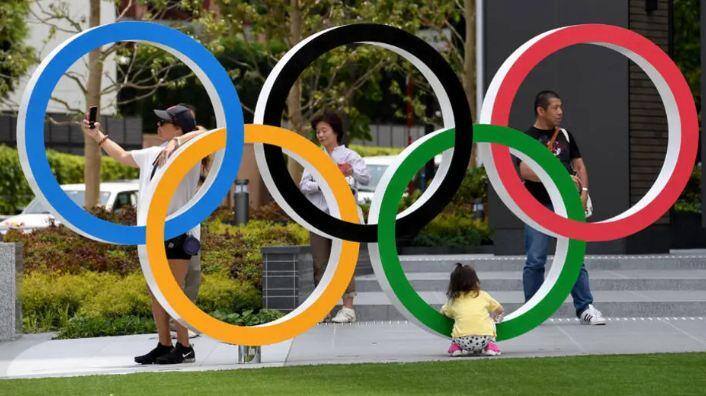 Populares tiram fotos nos anéis olímpicos na Praça Olímpica do Japão, ao lado do estádio nacional em Tóquio
