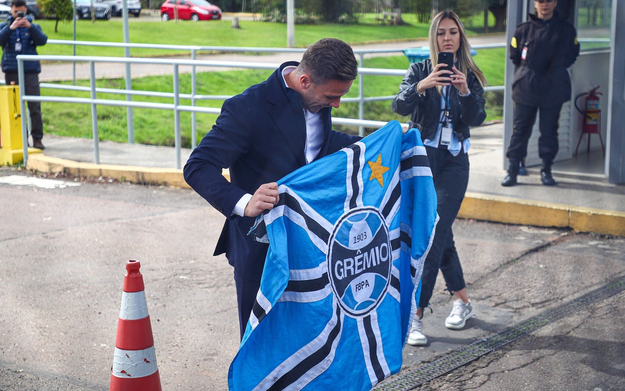 Arthur com bandeira do Grêmio após desembarcar no Aeroporto Salgado Filho. (Foto: Angelo Pieretti/Grêmio FBPA)