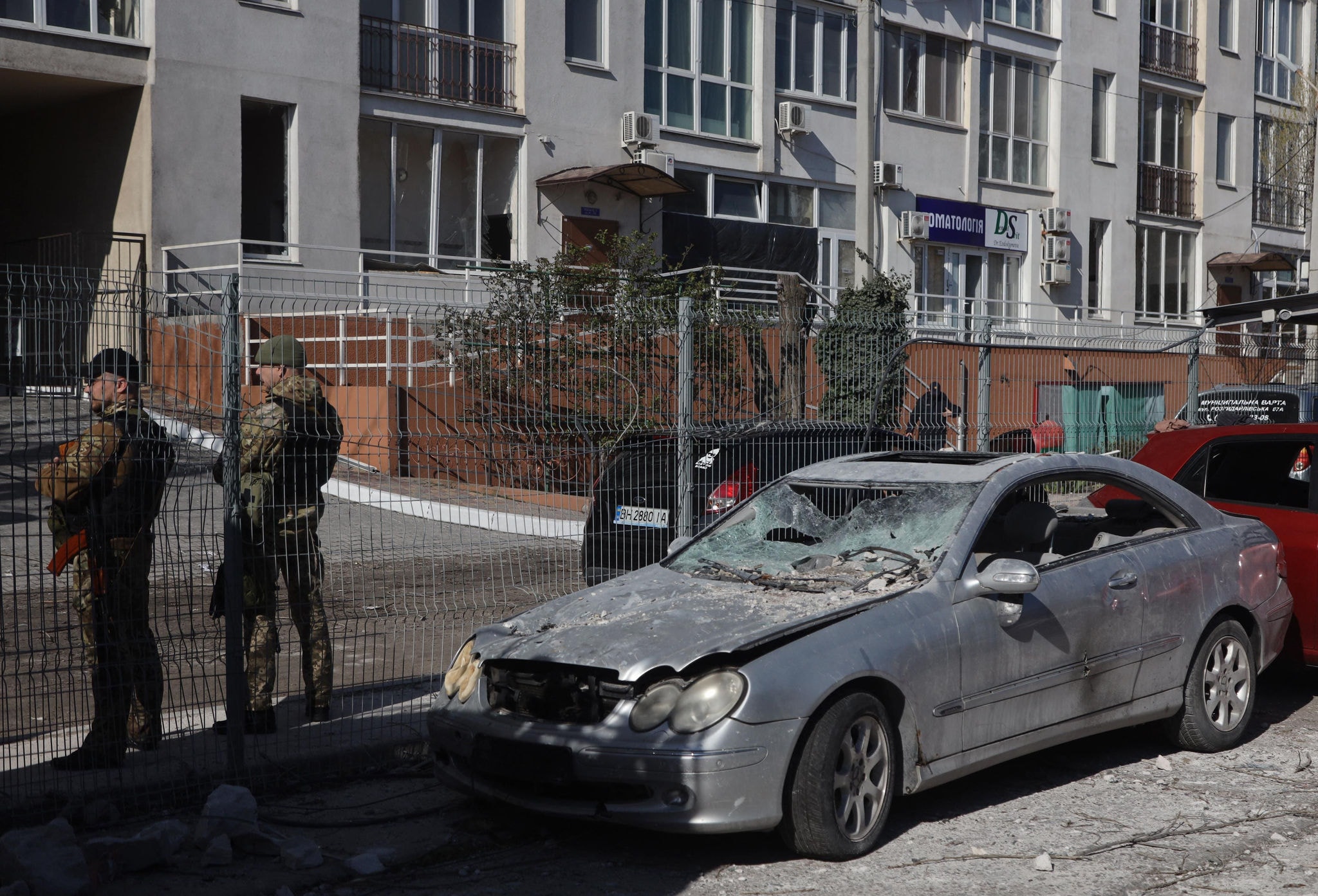 Militares ucranianos ao lado de um carro destruído em frente a um prédio danificado em Odessa, sul da Ucrânia.