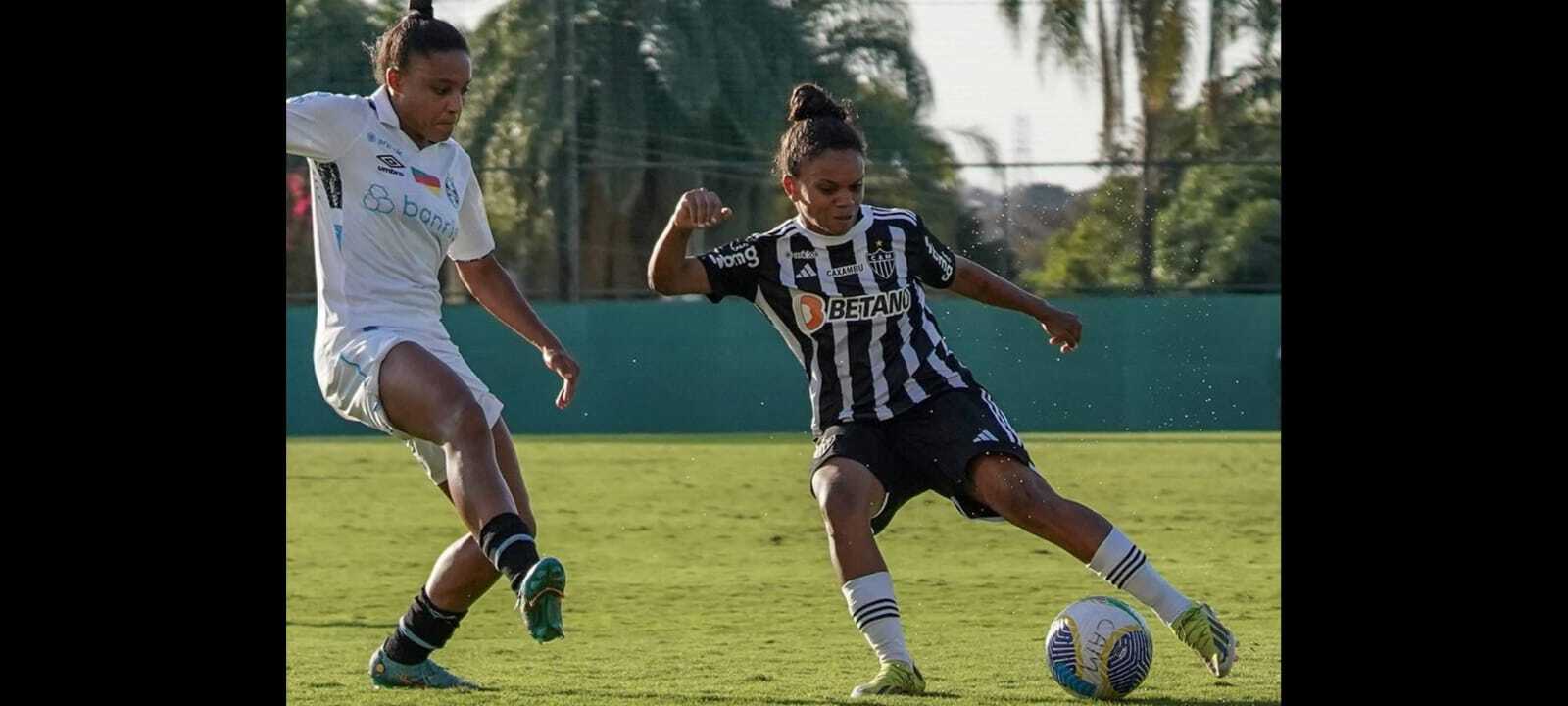 Jogadora do Atlético tenta o drible diante da marcação de volante do Grêmio