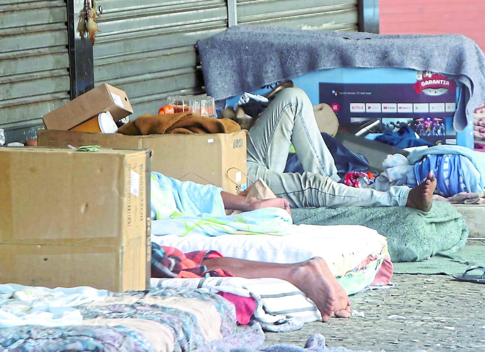 Pessoas em situação de rua deitadas em calçadas de Belo Horizonte