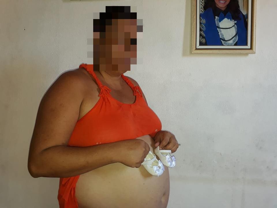 Mulher postava foto exibindo o sapatinho de uma criança na barriga