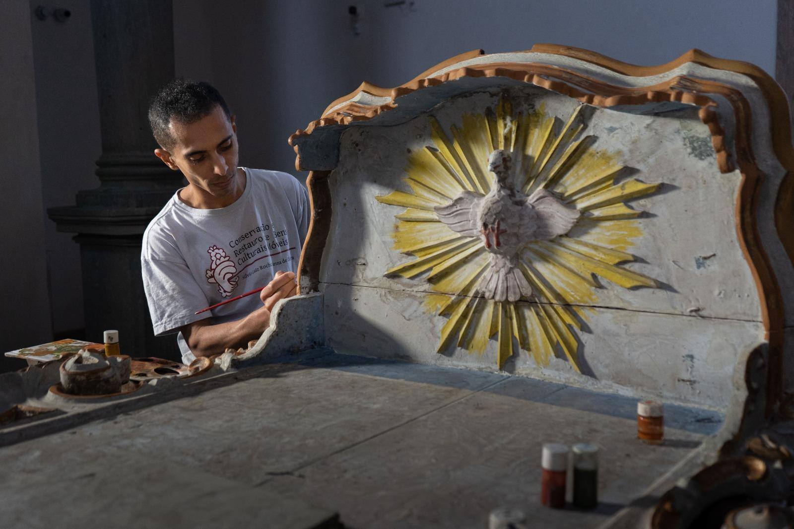 O técnico em conservação e restauração de bens culturais Edson Júnior Luciano realizando restauro de peça na Igreja de São Francisco de Assis, em Mariana