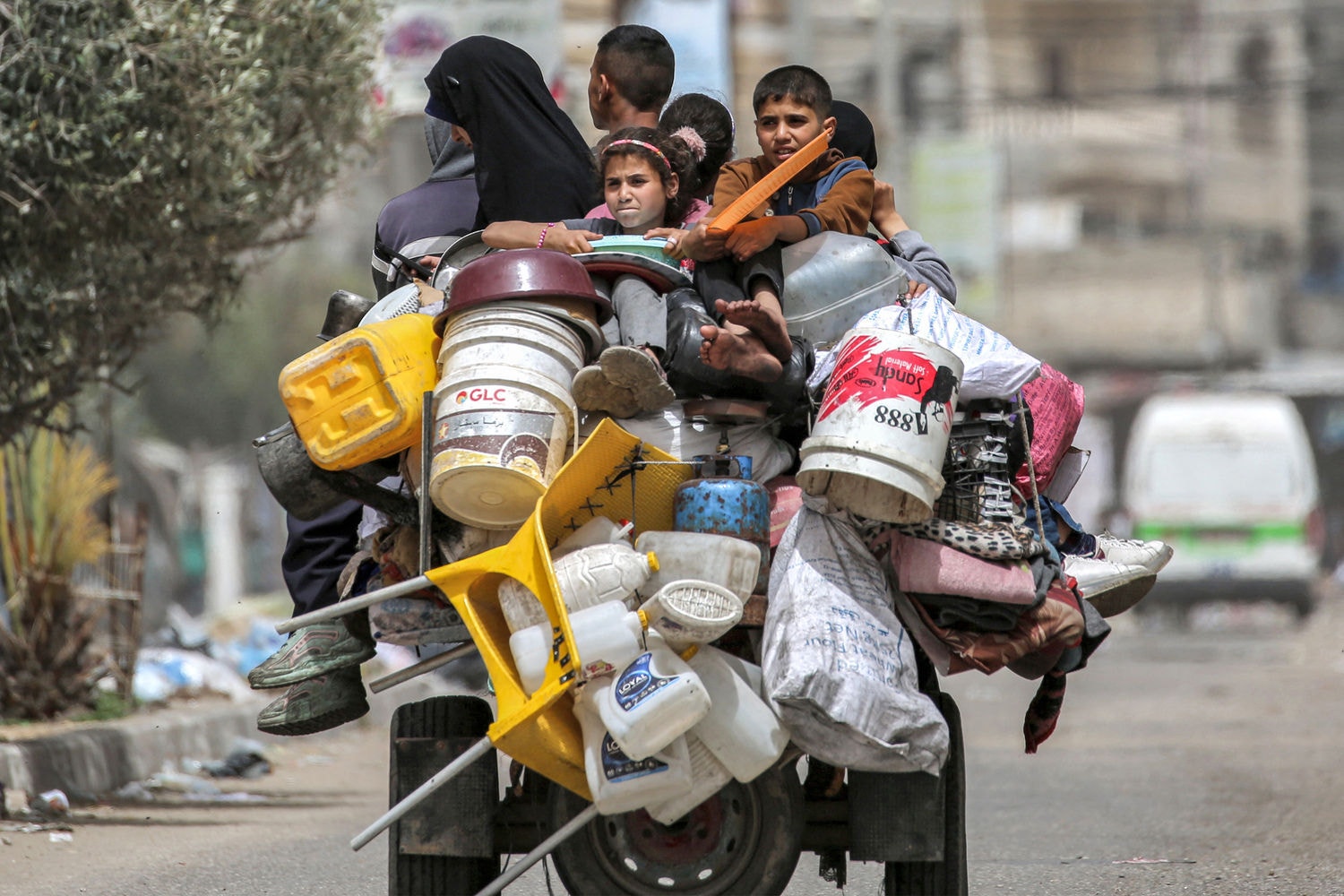 A man, woman, and children ride in the back of a tricycle loaded with belongings and other items as they flee bound for Khan Yunis, in Rafah in the southern Gaza Strip on May 11, 2024 amid the ongoing conflict in the Palestinian territory between Israel and Hamas. (Photo by AFP)