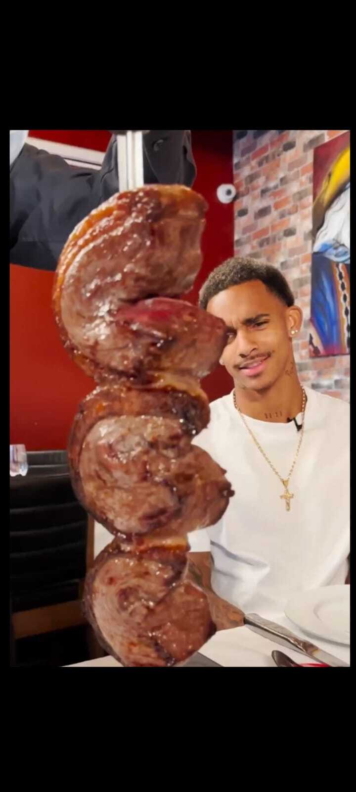Dylan Borrero com olhar fixo para espeto de churrasco