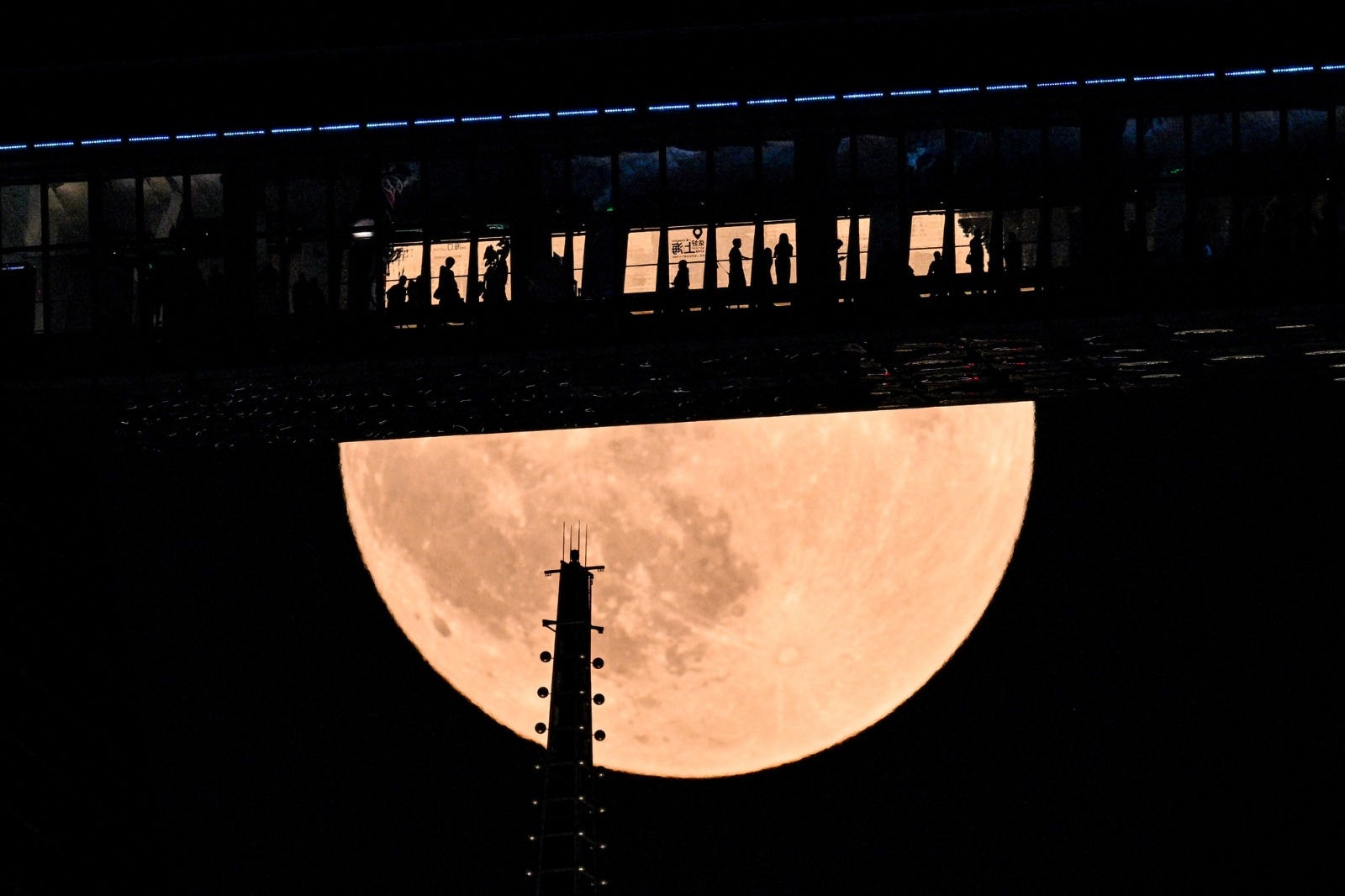 Pessoas são vistas em um andar do Shanghai World Financial Centre enquanto a "Lua de Sangue" surge acima dos arranha-céus