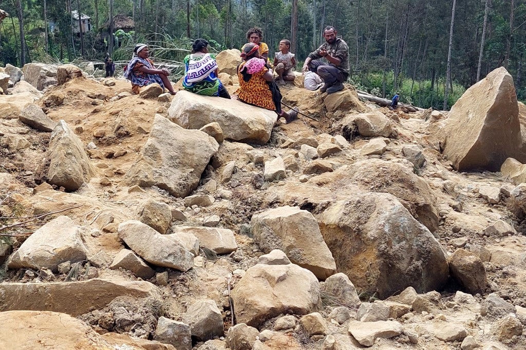 Membros da família de moradores desaparecidos são vistos no local de um deslizamento de terra na aldeia de Mulitaka