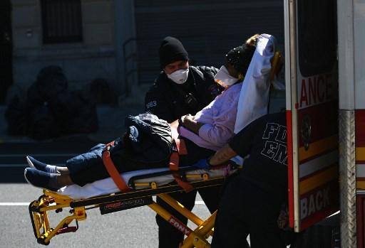 Paramédicos carregam uma maca com um paciente de uma ambulância no Brooklyn Hospital Center