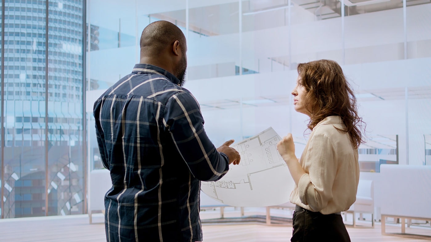 Business managers meeting with a realtor for a real estate office tour, planning an investment with detailed blueprints and architectural design. Examining layout sketches. Camera A.