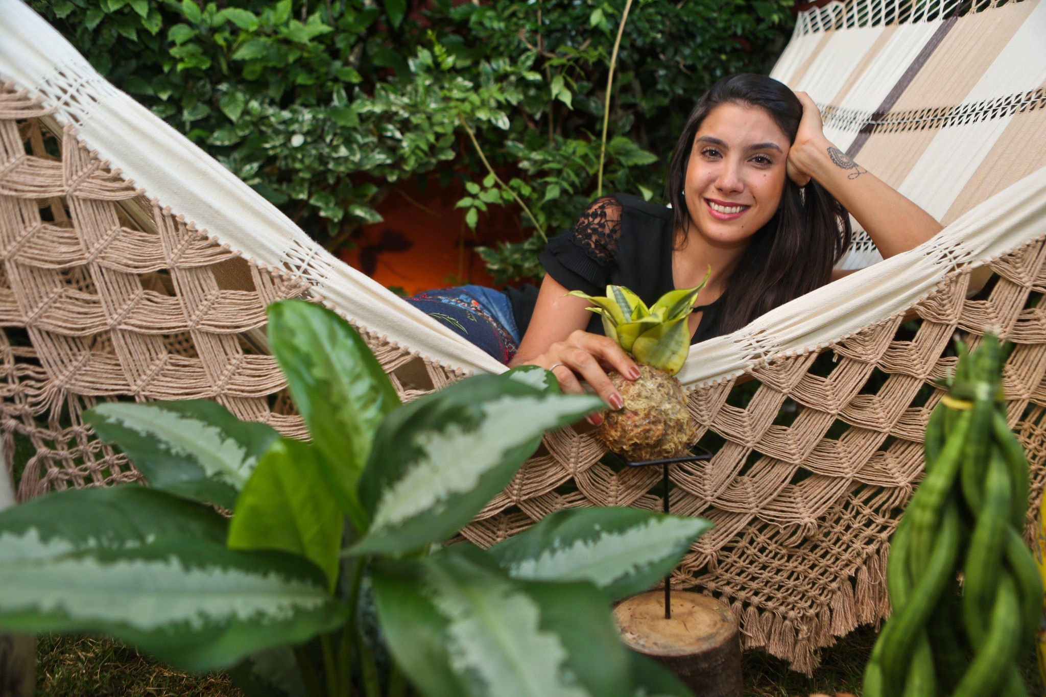 Maria Tereza segura um kokedama de espada-de-são-jorge, junto a outras de suas plantas favoritas: a comigo-ninguém-pode e a lança-de-são-jorge