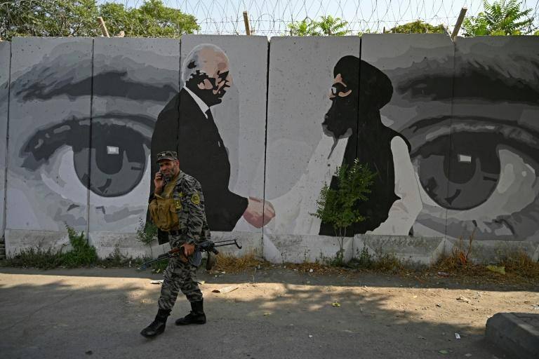 Soldado passa por muro que representa o emissário americano para o Afeganistão, Zalmay Khalilzad, e o cofundador dos talibãs Mulá Abdul Ghani Baradar em 31 de julho em Cabul