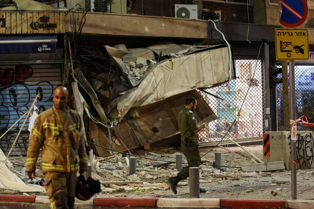Um socorrista caminha em frente a uma loja danificada em Tel Aviv, depois de ter sido atingido por um foguete disparado por militantes palestinos da Faixa de Gaza, em 7 de outubro de 2023