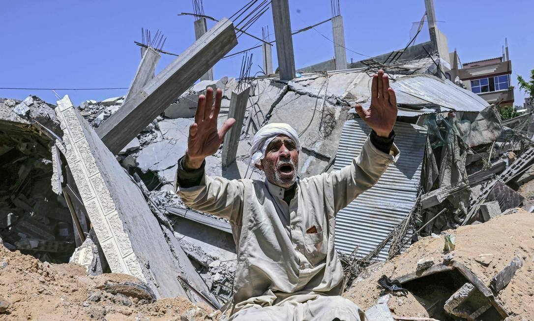 Palestino em frente a casa destruída