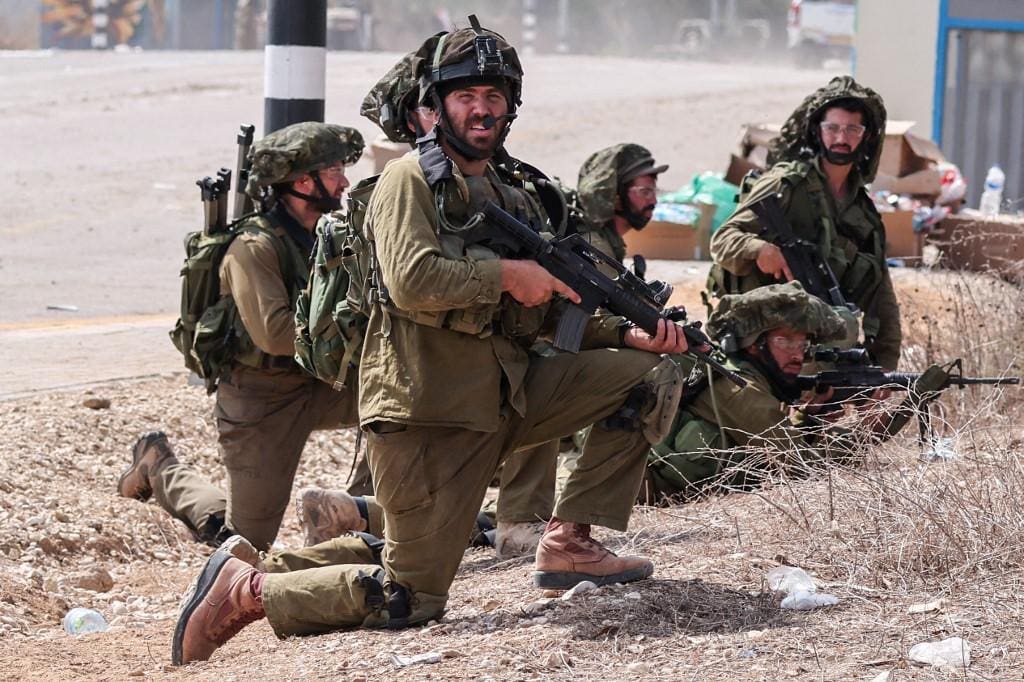 Soldados israelenses tomam posição ao lado de uma estrada em Kfar Aza, ao sul de Israel, na fronteira com a Faixa de Gaza, em 10 de outubro de 2023