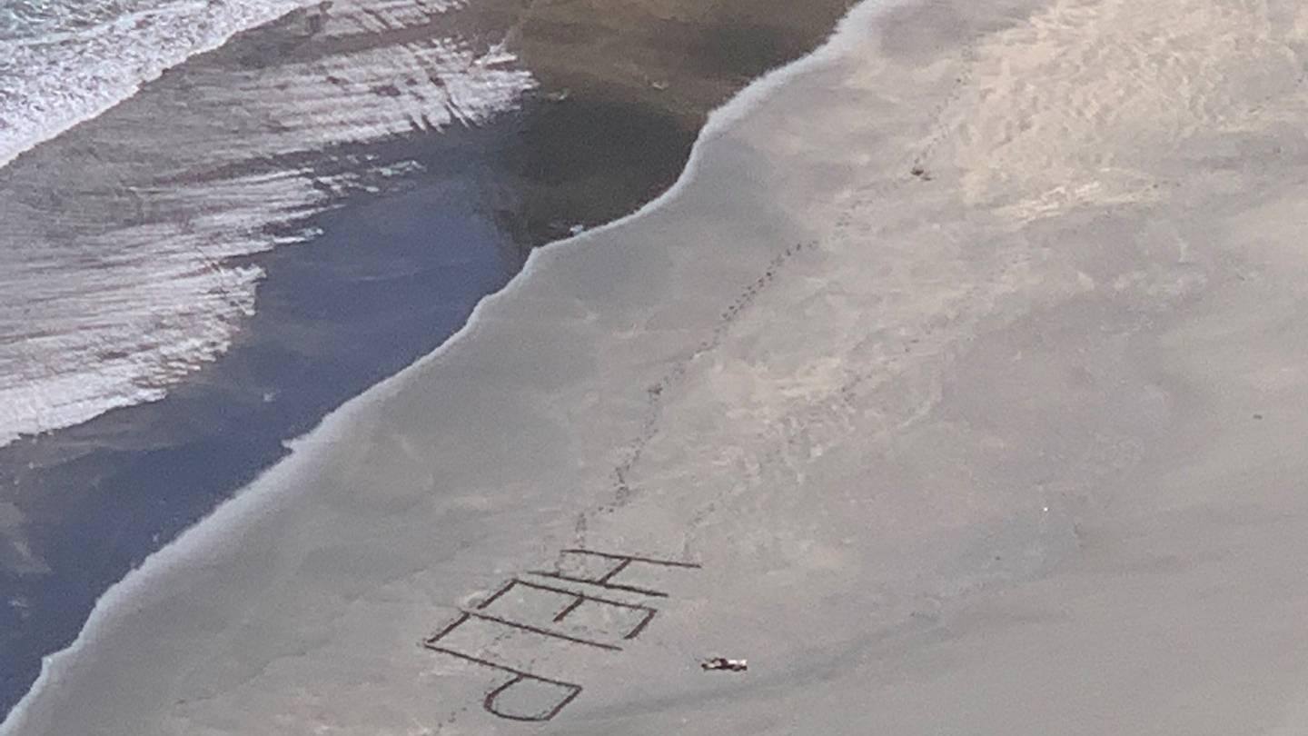 Surfista pede socorro escrevendo na areia