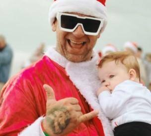 Surfista vestido de papai noel participa do Surfing Santa, na Califórnia