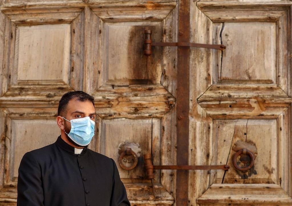 Padre usa máscara em frente à Igreja do Santo Sepulcro, em Jerusalém